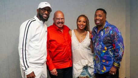 tom joyner in red shirt black pants standing with other 3 people from the radio 